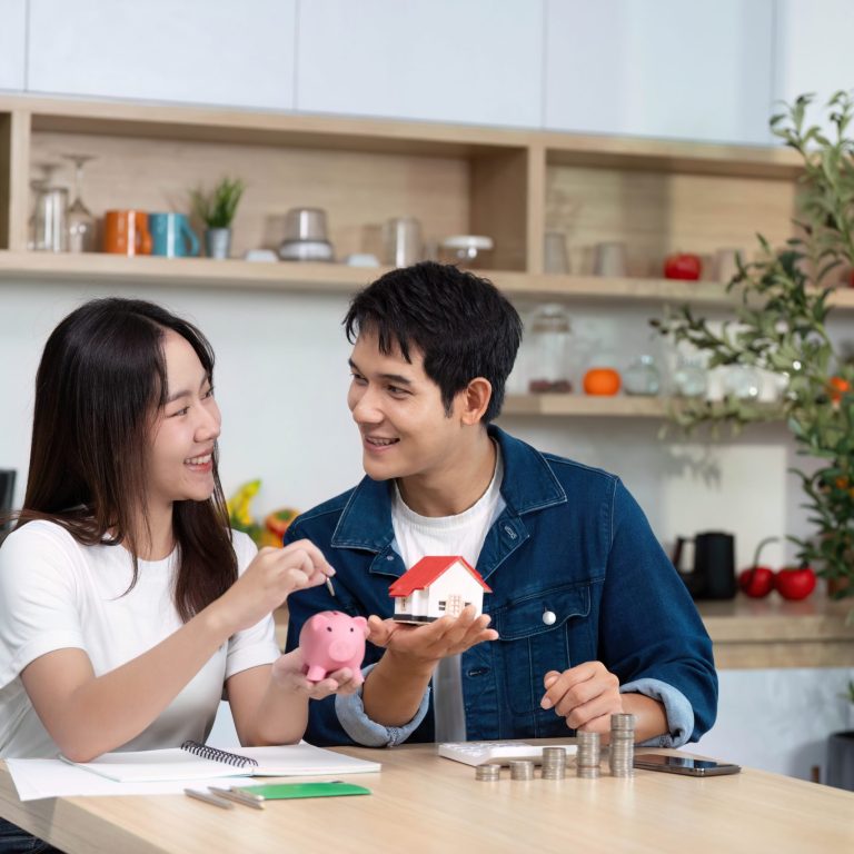 一对年轻人正拿着储蓄罐和房屋模型开心地交流。